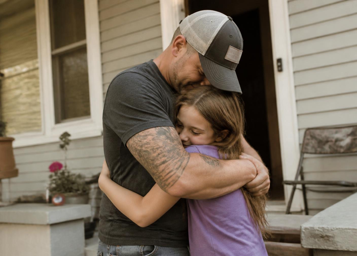A veteran holding his daughter on the porch of their home